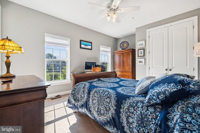 bedroom featuring a closet, light carpet, baseboards, and ceiling fan