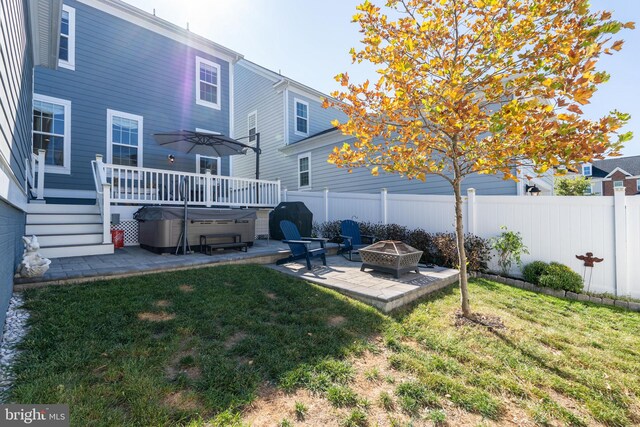 back of property with fence, an outdoor fire pit, a yard, a hot tub, and a patio area