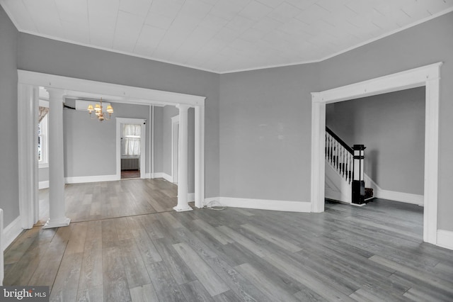 unfurnished living room featuring wood-type flooring, radiator, ornamental molding, and a notable chandelier