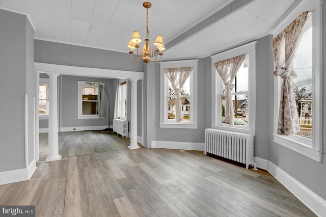 unfurnished dining area featuring ornate columns, radiator heating unit, and plenty of natural light