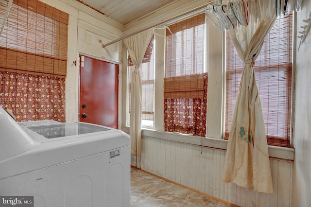 washroom with wooden walls and washer / dryer