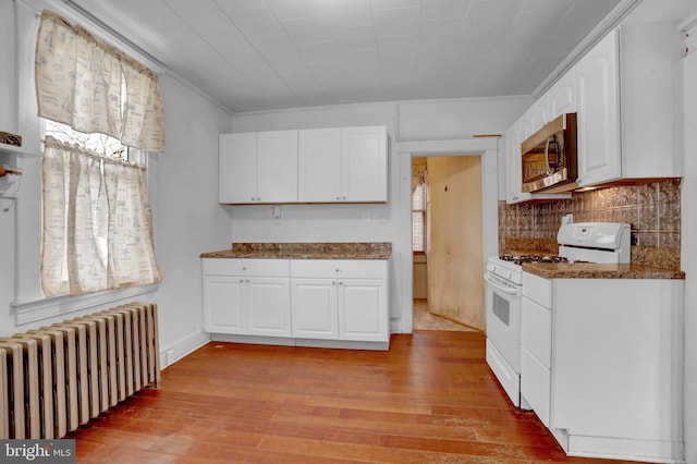 kitchen featuring radiator, gas range gas stove, white cabinets, and light hardwood / wood-style floors