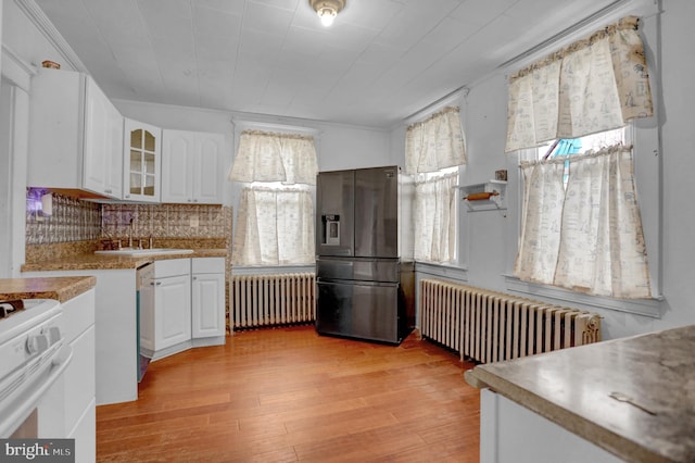 kitchen featuring white cabinets, radiator heating unit, white appliances, and light hardwood / wood-style flooring