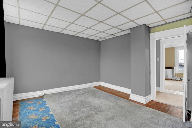 spare room featuring hardwood / wood-style flooring and a drop ceiling