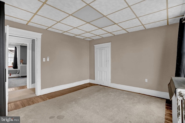 spare room with hardwood / wood-style floors, a paneled ceiling, and radiator