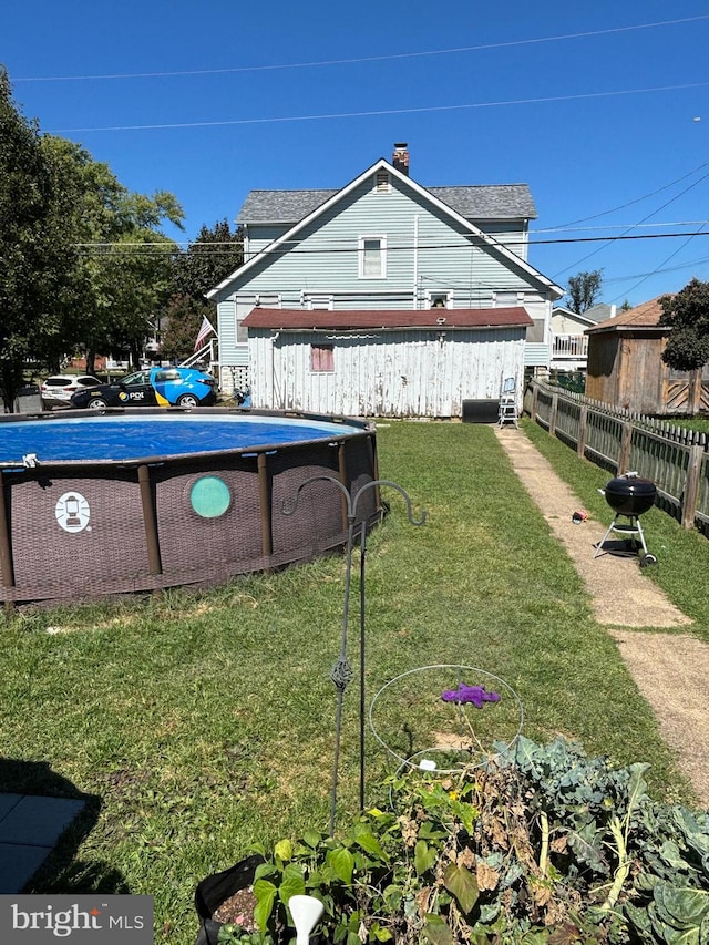 rear view of property featuring a fenced in pool and a yard