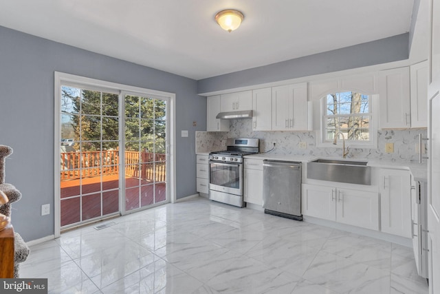 kitchen with a sink, stainless steel appliances, light countertops, under cabinet range hood, and marble finish floor