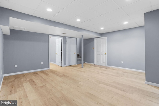 finished below grade area featuring visible vents, baseboards, a drop ceiling, recessed lighting, and light wood-style flooring