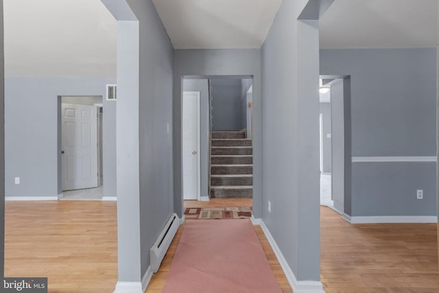 hallway with stairs, baseboards, light wood finished floors, and a baseboard radiator