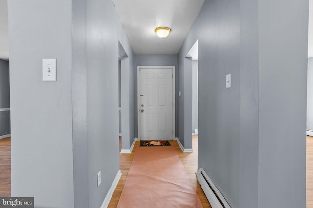 doorway to outside featuring baseboard heating, light wood-style flooring, and baseboards