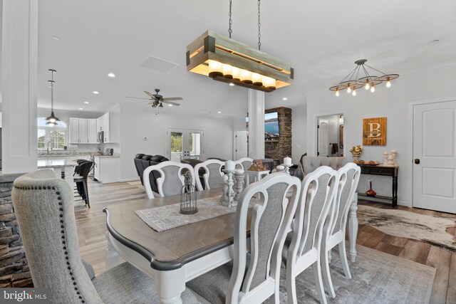 dining area with ceiling fan with notable chandelier, light hardwood / wood-style floors, crown molding, and sink