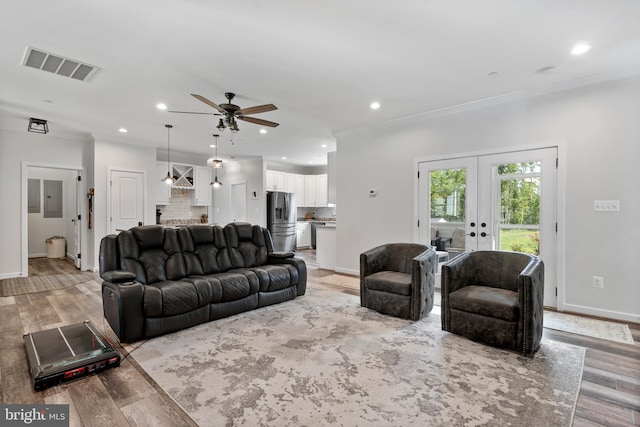 living room featuring ceiling fan, electric panel, french doors, light hardwood / wood-style flooring, and crown molding