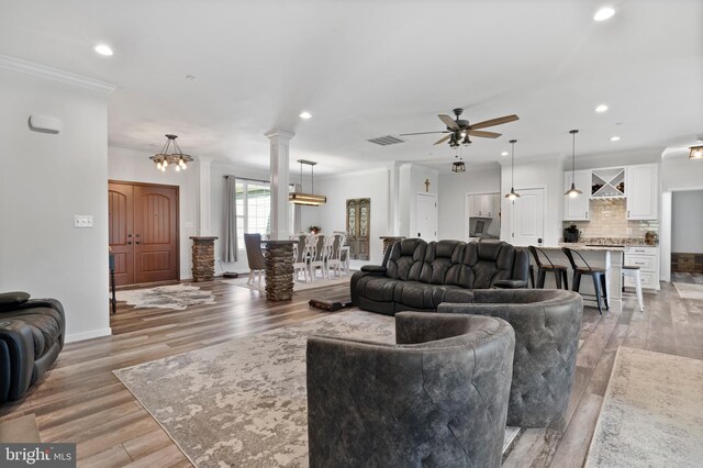 living room with hardwood / wood-style flooring, ceiling fan with notable chandelier, and ornamental molding