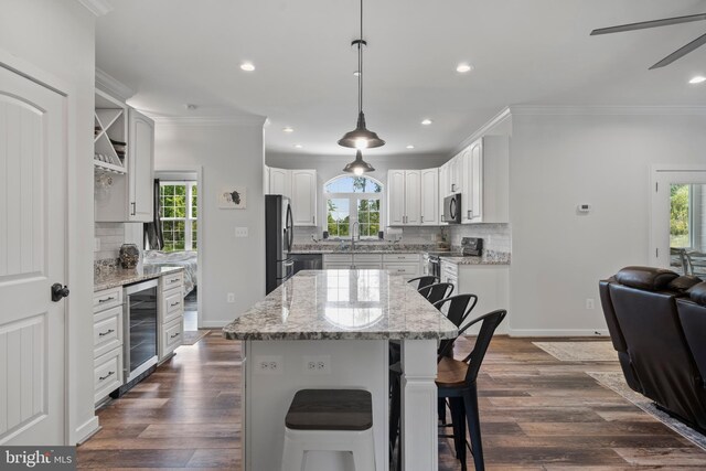 kitchen with white cabinets, wine cooler, a kitchen island, dark wood-type flooring, and stainless steel appliances