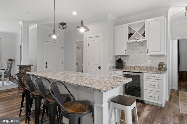 kitchen featuring pendant lighting, wine cooler, a center island, dark wood-type flooring, and white cabinetry