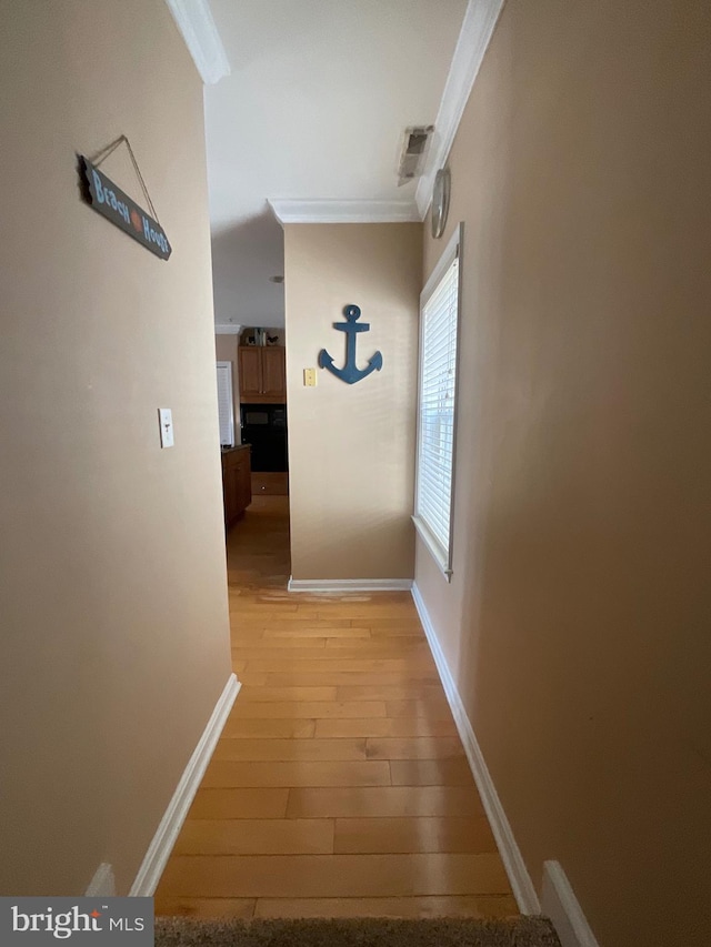 hall featuring light wood-type flooring and ornamental molding