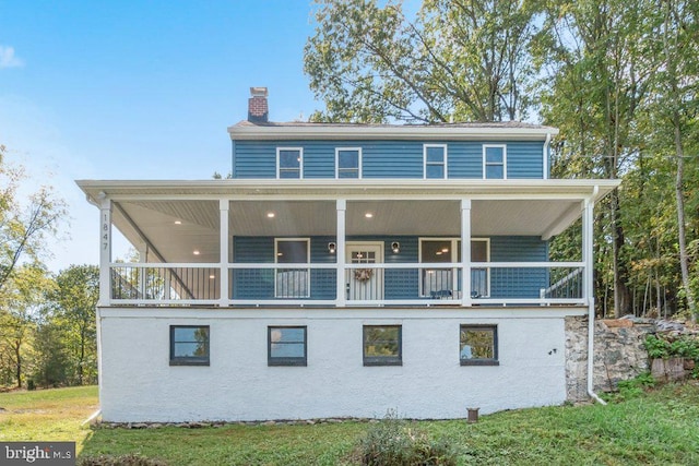 back of property featuring a lawn and a balcony