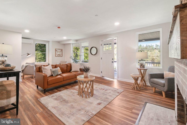 living room featuring a wealth of natural light, a wall unit AC, and hardwood / wood-style flooring