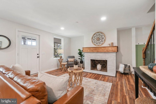 living room with a brick fireplace and dark hardwood / wood-style floors