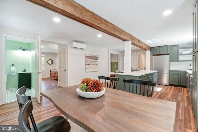 dining area with beam ceiling, a wall unit AC, and hardwood / wood-style flooring