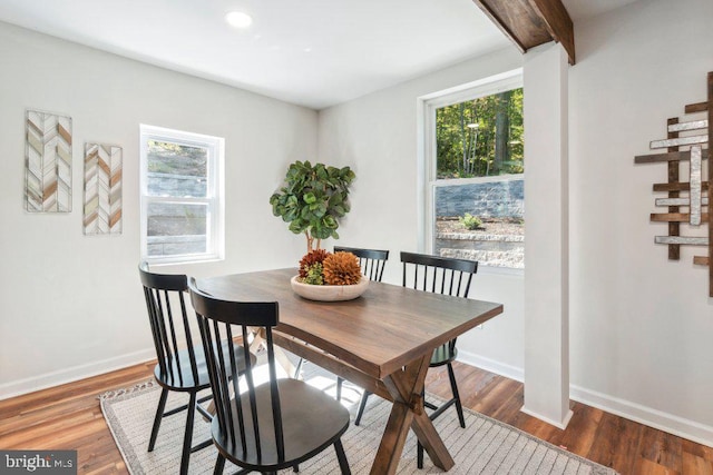 dining space featuring a wealth of natural light, wood-type flooring, and beamed ceiling