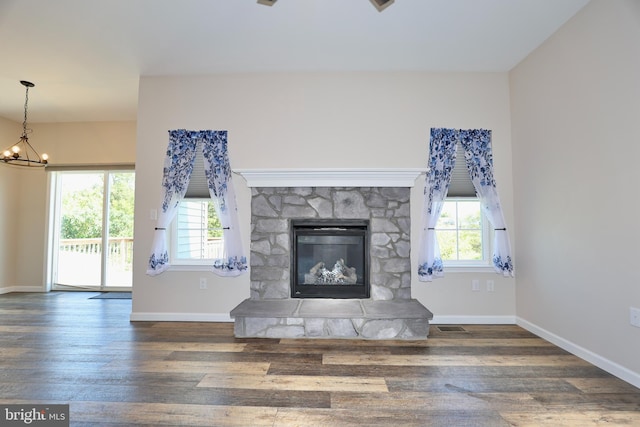 unfurnished living room with wood-type flooring, a fireplace, and a chandelier