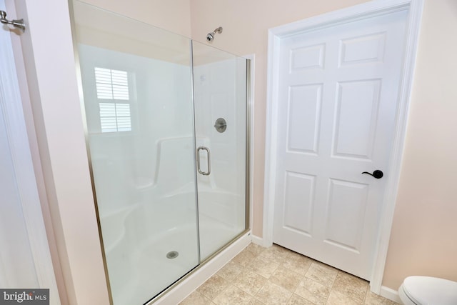 bathroom with toilet and a shower with shower door