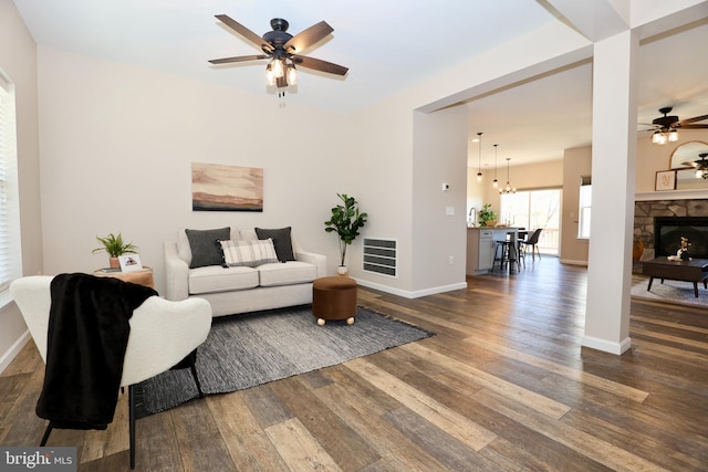 living area with visible vents, a ceiling fan, wood finished floors, a fireplace, and baseboards