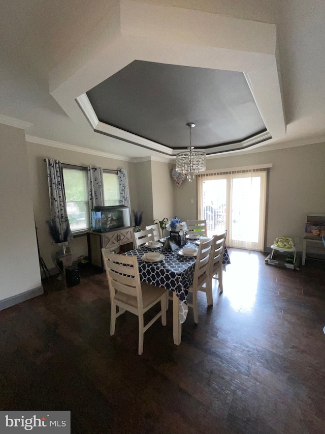 dining area featuring an inviting chandelier, ornamental molding, a tray ceiling, and dark wood-type flooring