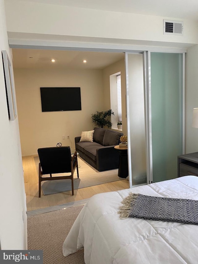 bedroom with a closet, recessed lighting, wood finished floors, and visible vents