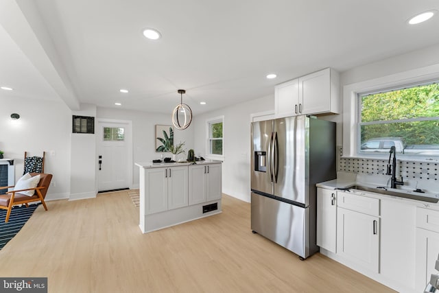 kitchen with decorative light fixtures, light wood-type flooring, white cabinetry, sink, and stainless steel fridge with ice dispenser