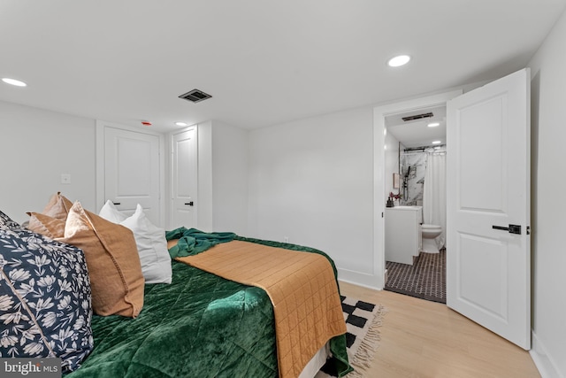 bedroom with light wood-type flooring and ensuite bathroom