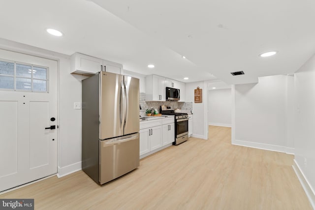 kitchen featuring appliances with stainless steel finishes, white cabinetry, and light hardwood / wood-style flooring