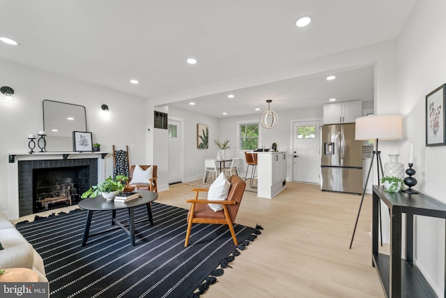 living room featuring light wood-type flooring and a brick fireplace