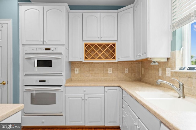 kitchen featuring white cabinets, double oven, and a sink