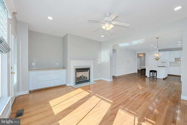 unfurnished living room featuring light hardwood / wood-style flooring and ceiling fan