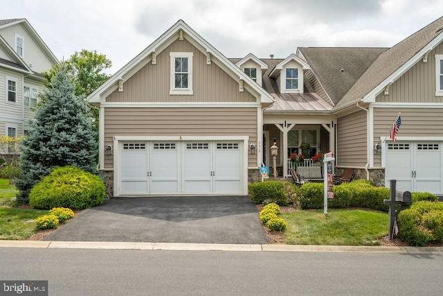 view of front facade featuring stone siding, covered porch, driveway, and an attached garage