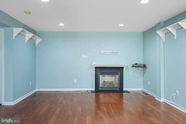 unfurnished living room featuring recessed lighting, baseboards, a fireplace with flush hearth, and wood finished floors