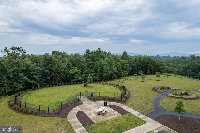 surrounding community featuring a patio area, a view of trees, a yard, and fence