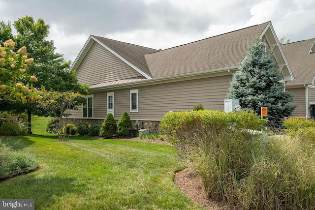 view of side of home featuring a yard and roof with shingles