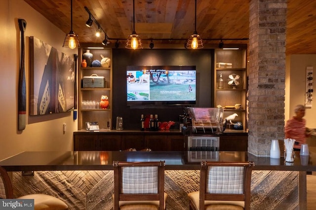 bar featuring hanging light fixtures, track lighting, wood ceiling, and bar area