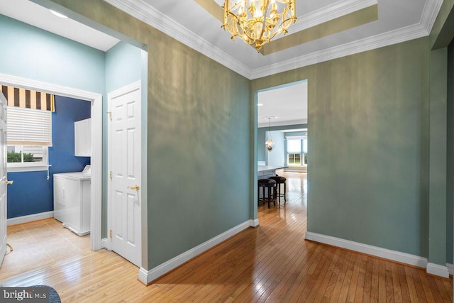 corridor featuring an inviting chandelier, crown molding, baseboards, and light wood-type flooring