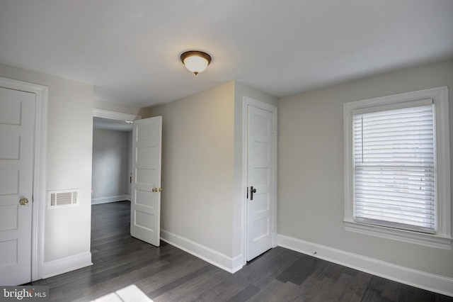 unfurnished bedroom with multiple windows and dark hardwood / wood-style floors