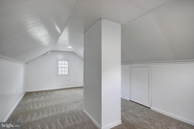 bonus room with wood walls, light carpet, and vaulted ceiling