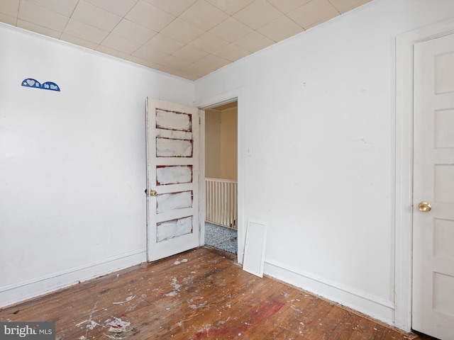 empty room with dark hardwood / wood-style floors and crown molding