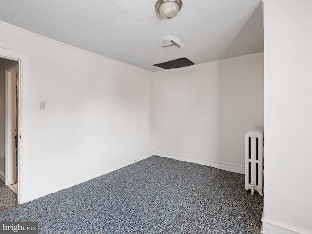 empty room featuring carpet, radiator heating unit, and a textured ceiling