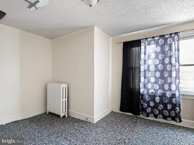 empty room featuring radiator heating unit, a textured ceiling, and dark colored carpet