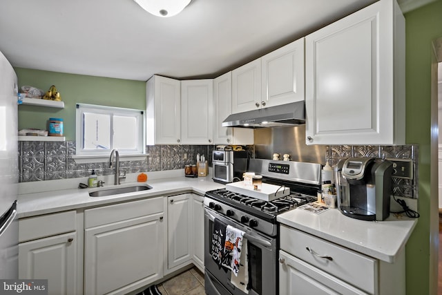 kitchen featuring stainless steel gas range, sink, tasteful backsplash, and white cabinetry