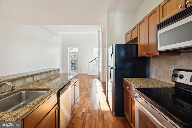 kitchen with light stone counters, appliances with stainless steel finishes, and sink