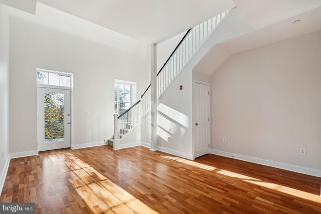 entryway with hardwood / wood-style flooring and a towering ceiling